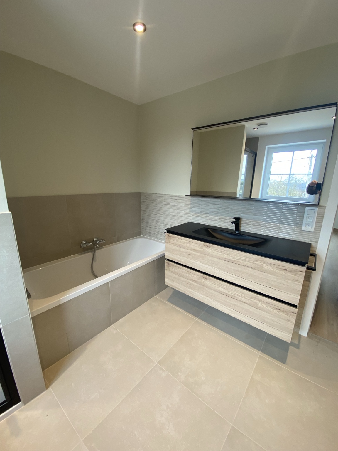 Salle de bain claire avec baignoire et meuble vasque suspendu