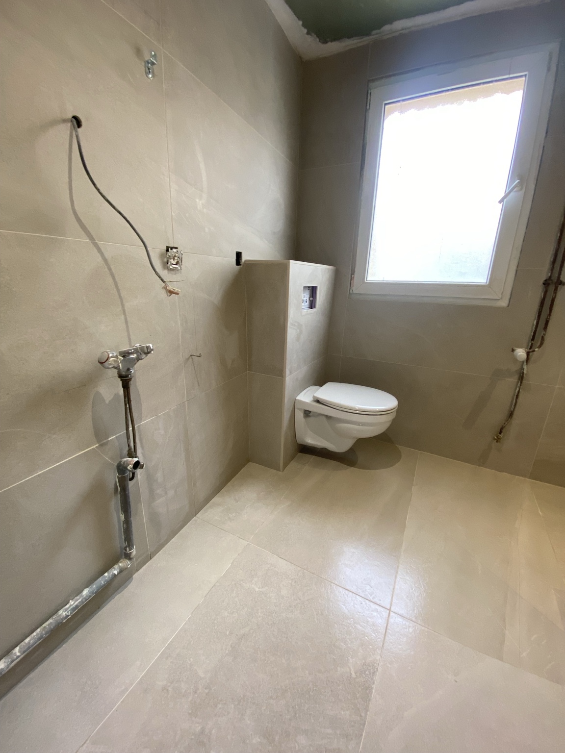 Salle de bain carrelée avec WC suspendu en cours de finition