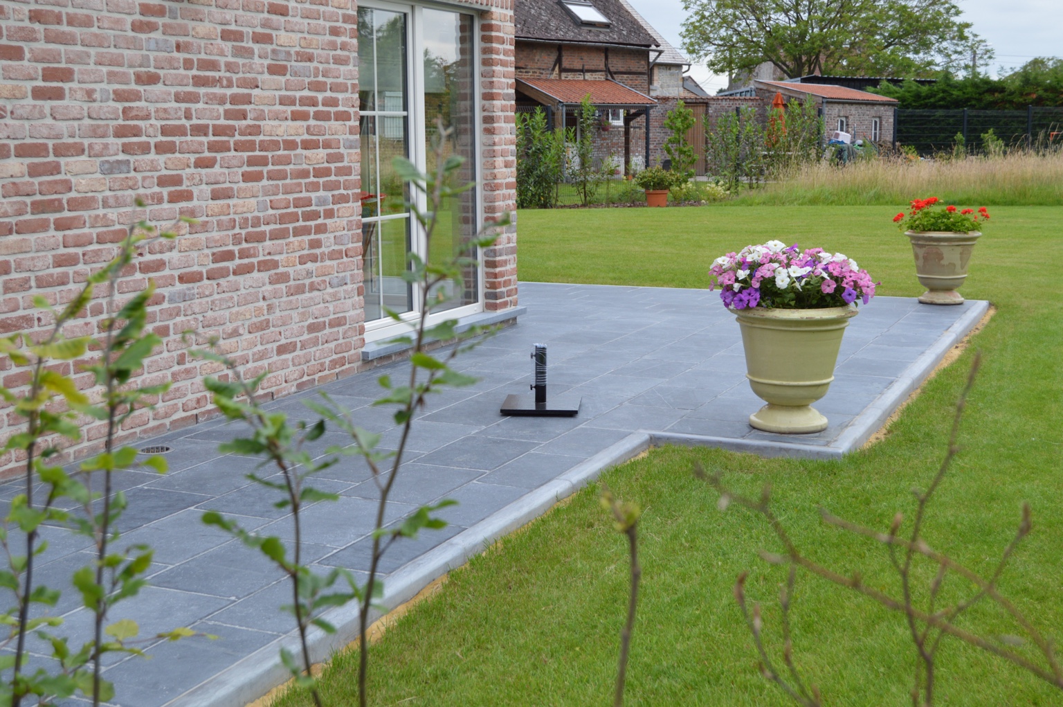 Terrasse en pierre naturelle aménagée autour d’une maison